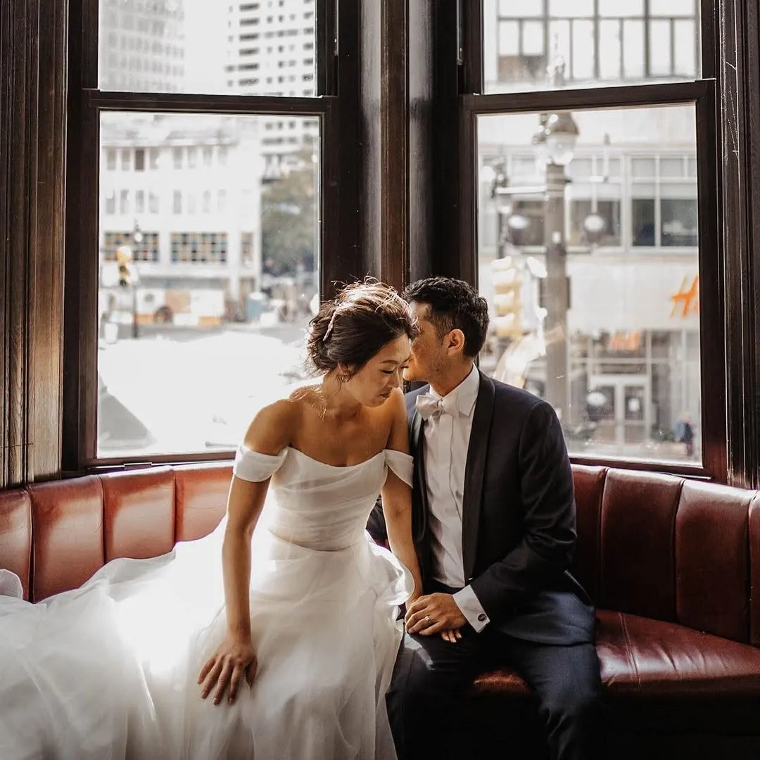 A wedding couple seated by the bay windows at Wright & Company