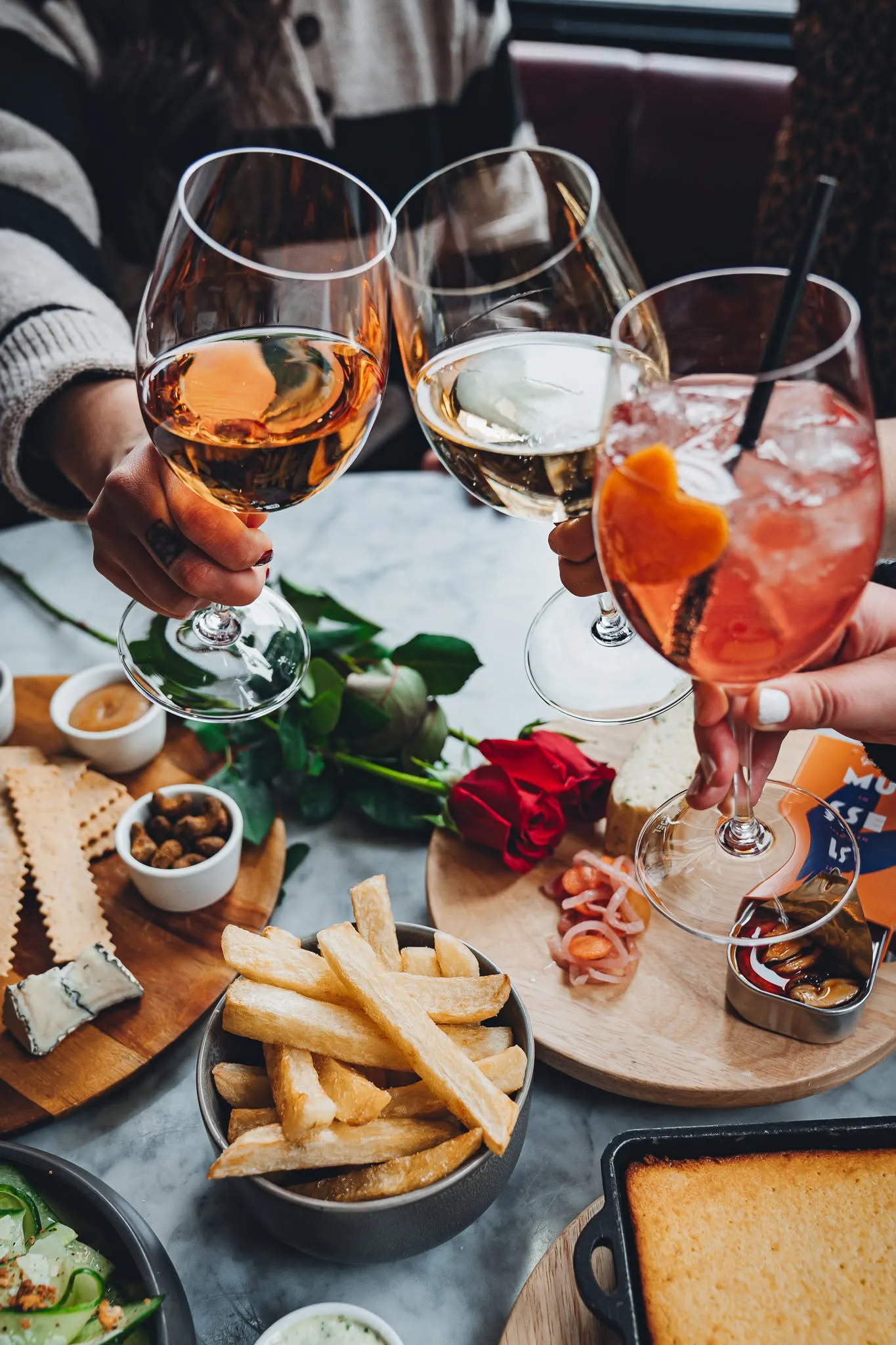 Three guests raising glasses in a toast over a shared table at Wright & Company