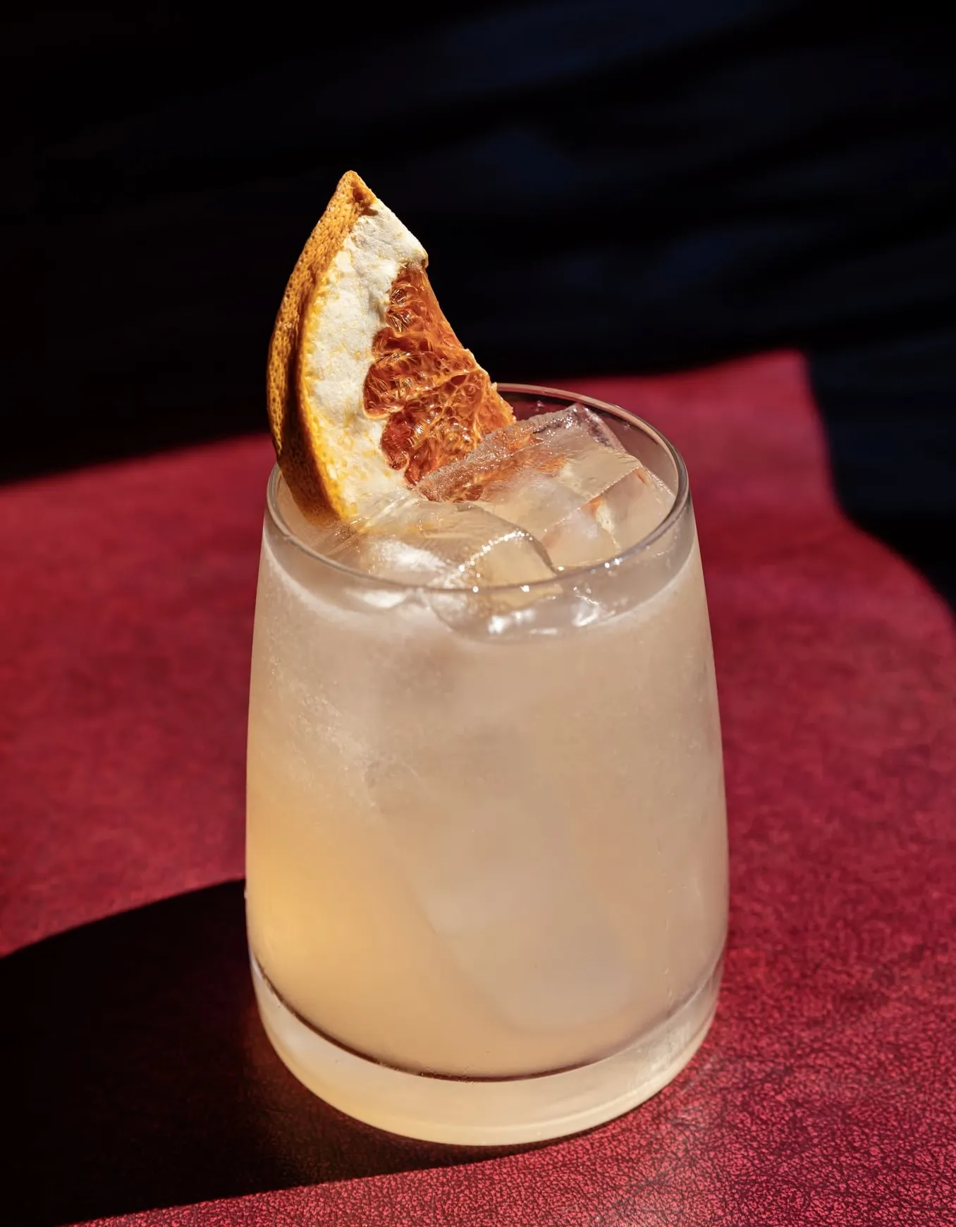 A cocktail with a charred citrus garnish on the marble bar at Wright & Company