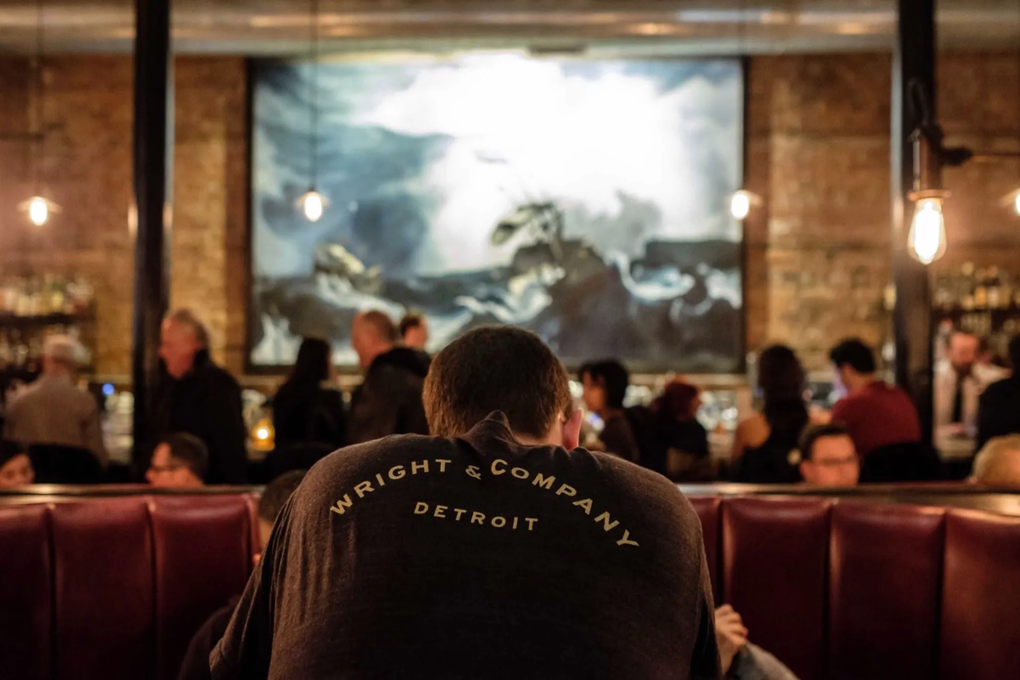 Guests gathered in the Wright & Company dining room beneath the ship mural, a server in a Wright & Company Detroit jacket in the foreground